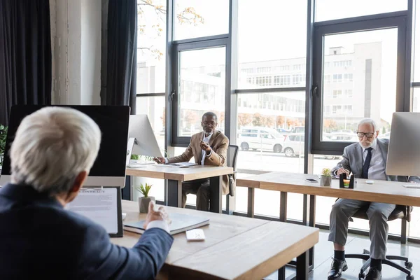 Blurred businessman working with multicultural coworkers in office — Stock Photo