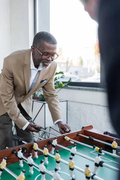 Empresário americano africano sênior jogando futebol de mesa com colega turvo — Fotografia de Stock