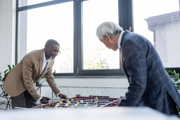 Senior interracial businessmen playing table football in office — Stock Photo