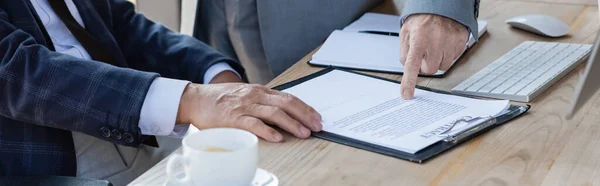 Abgeschnittene Ansicht eines leitenden Geschäftsmannes, der auf Vertrag in der Nähe eines Kollegen zeigt, Banner — Stockfoto