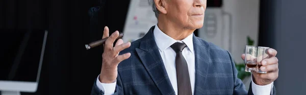 Cropped view of senior businessman with cigar and glass of whiskey in office, banner — Stock Photo