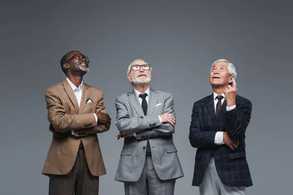 Senior asian businessman pointing up with finger near multiethnic colleagues isolated on grey — Stock Photo