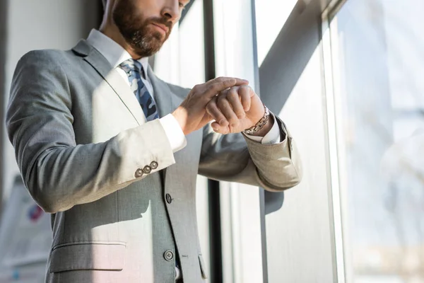 Vue recadrée de l'homme d'affaires regardant montre-bracelet dans le bureau — Photo de stock