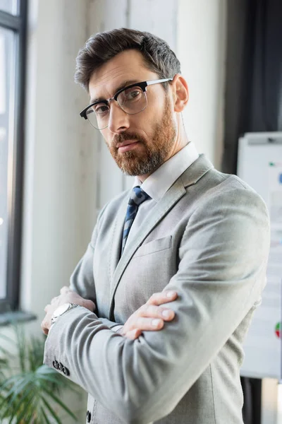 Businessman in formal wear standing with crossed arms in office — Stock Photo