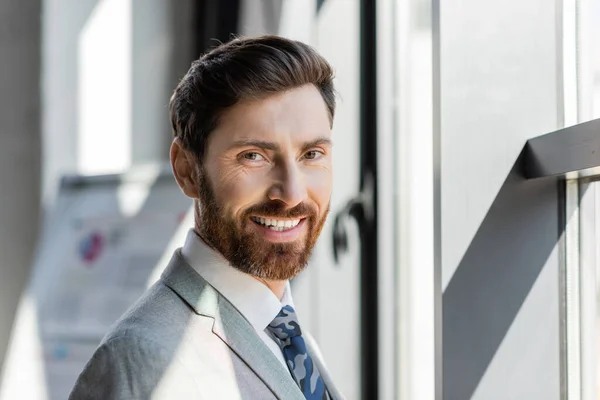 Porträt eines Geschäftsmannes im Anzug, der im Büro in die Kamera lächelt — Stockfoto