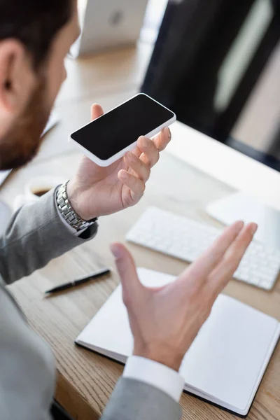 Empresário desfocado gravando mensagem de voz no celular no escritório — Fotografia de Stock
