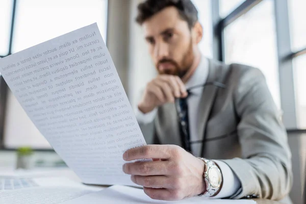 Papel na mão de empresário desfocado que trabalha no escritório — Fotografia de Stock