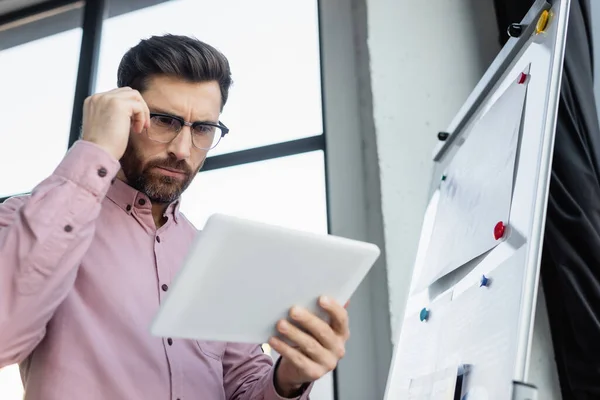 Visão de baixo ângulo de empresário usando tablet digital perto de flip chart no escritório — Fotografia de Stock