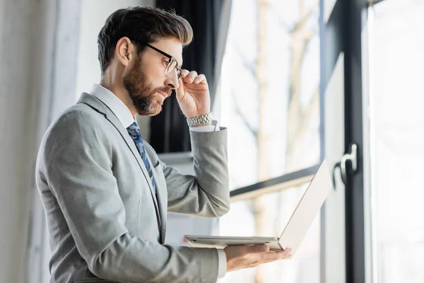 Side view of businessman in formal wear using laptop in office — Stock Photo