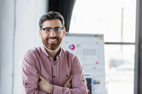 Smiling businessman in eyeglasses and shirt looking at camera in office — Stock Photo