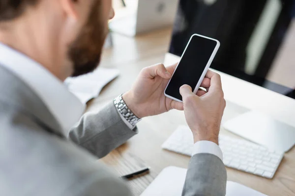 Cropped view of businessman using smartphone with blank screen in office — Stock Photo