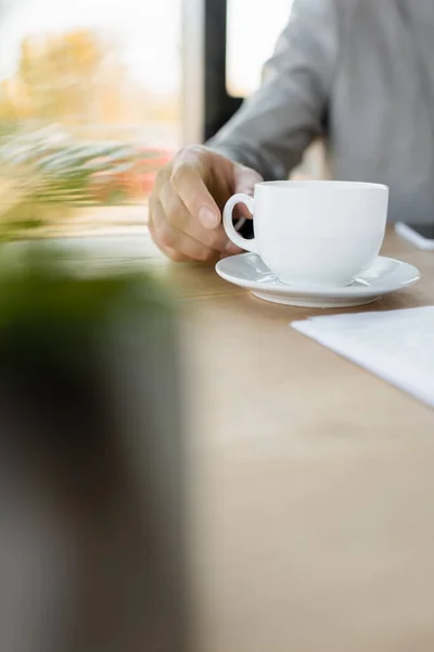 Cropped view of businessman taking cup of coffee in office — Stock Photo