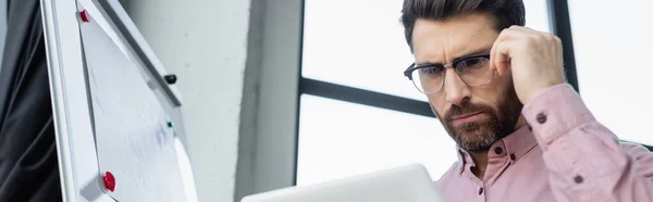 Homem de negócios focado usando tablet digital perto de flip chart no escritório, banner — Fotografia de Stock