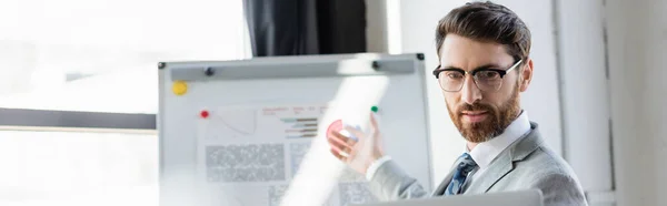 Businessman having video call on laptop near blurred flip chart in office, banner — Stock Photo