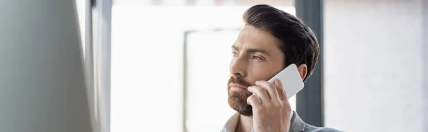 Uomo d'affari barbuto che parla su smartphone in ufficio, banner — Foto stock