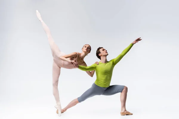 Full length of flexible young ballet dancers on grey — Stock Photo