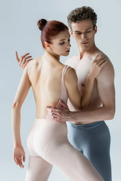 Bailarina elegante dançando com parceiro sem camisa isolado em cinza — Fotografia de Stock