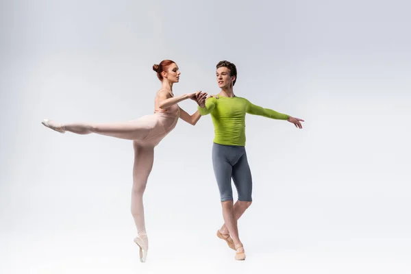 Toute la longueur des danseurs élégants exécutant la danse de ballet sur le gris — Photo de stock