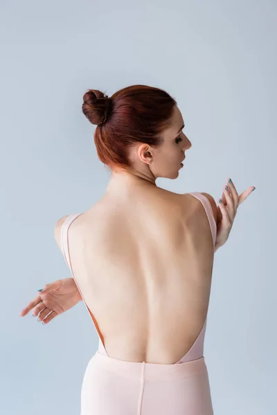 Sensuelle jeune ballerine en body se serrant dans ses bras pendant la danse isolée sur gris — Photo de stock