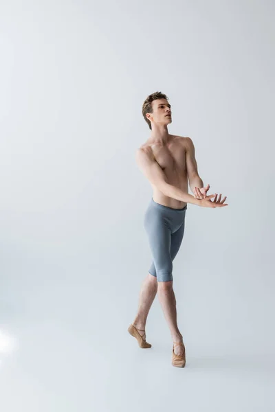 Full length of graceful ballet dancer gesturing on grey — Stock Photo