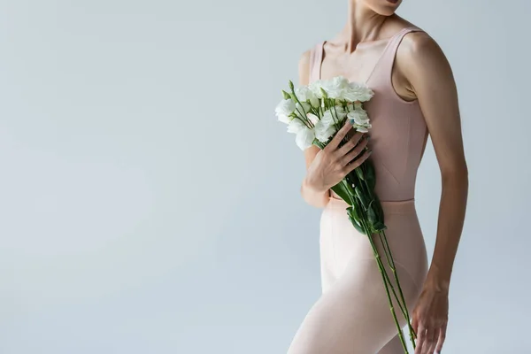 Vista recortada de la joven bailarina sosteniendo ramo de flores aisladas en gris - foto de stock