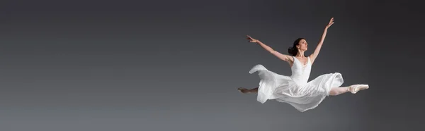 Piena lunghezza di donna graziosa in abito bianco saltando isolato su grigio, banner — Foto stock