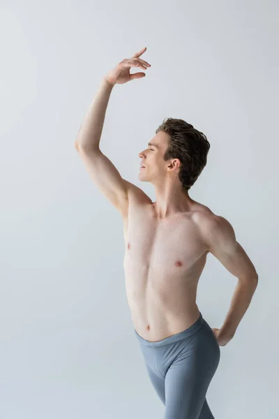 Giovane uomo senza maglietta con mano sollevata che esegue danza classica isolata su grigio — Foto stock