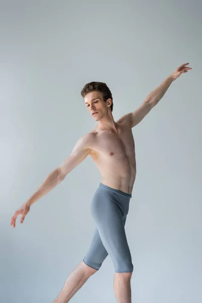 Hombre sin camisa con las manos extendidas realizando danza de ballet aislado en gris - foto de stock