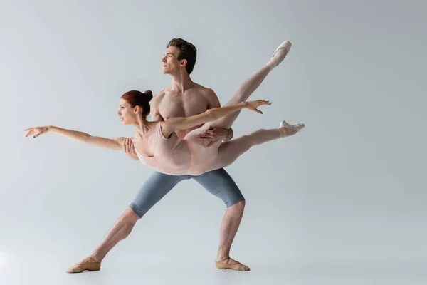 Bailarina sem camisa levantando bailarina jovem isolado em cinza — Fotografia de Stock