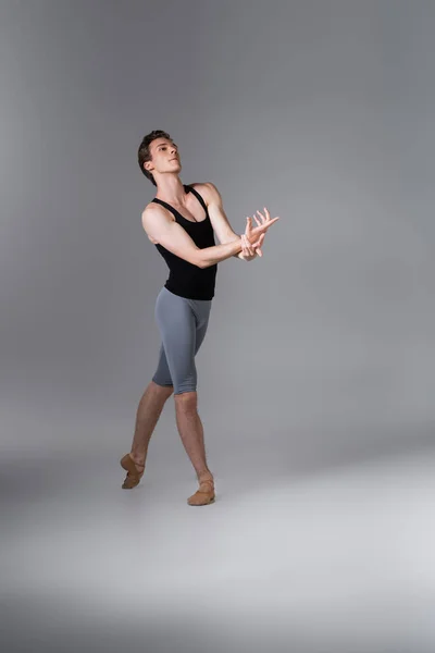 Comprimento total de dança graciosa ballet bailarino gestos durante a realização de dança balé em cinza escuro — Fotografia de Stock