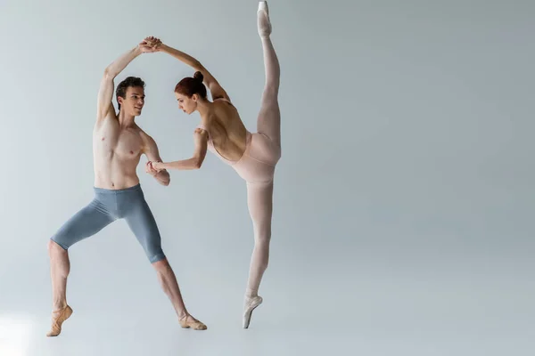 Longueur totale de jeune danseuse de ballet gaie dansant danse de ballet avec ballerine sur gris — Photo de stock