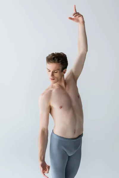 Graceful and shirtless dancer with outstretched hand performing ballet dance isolated on gray — Stock Photo