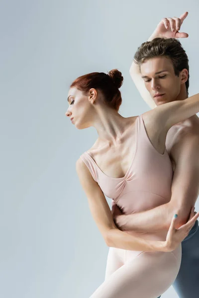 Homem dançando com bailarina graciosa isolado em cinza — Fotografia de Stock