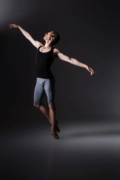 Elegant man gesturing while performing ballet dance on black — Stock Photo