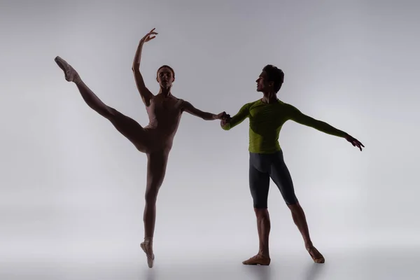 Silueta de bailarina cogida de la mano con bailarina sobre gris - foto de stock