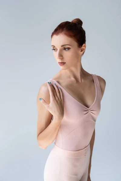 Redhead and young ballerina in bodysuit dancing while looking away isolated on gray — Stock Photo