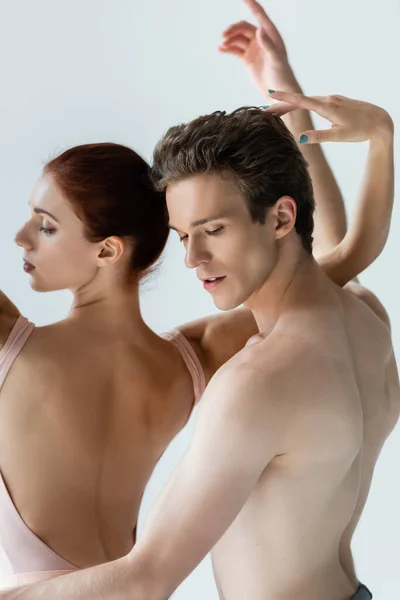 Рыжая женщина и мужчина без рубашки танцует балет, изолированный на сером — стоковое фото
