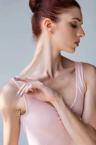 Чувственная молодая балерина в боди-костюме, танцующая изолированная на сером — стоковое фото