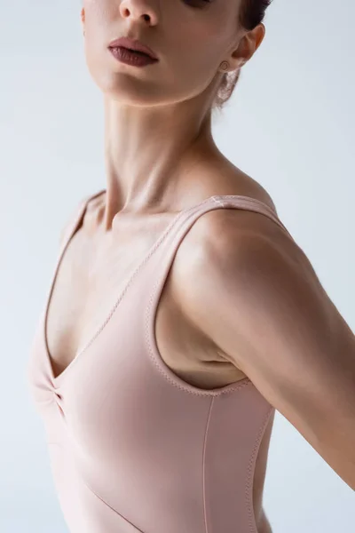 Частичный вид молодой балерины в телесном костюме, изолированном на сером — стоковое фото