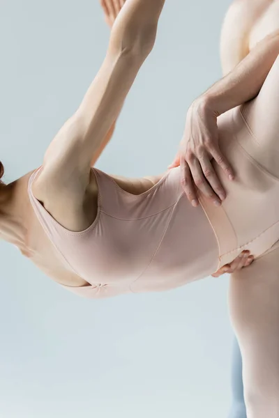 Partial view of flexible ballerina dancing ballet with partner isolated on gray — Stock Photo