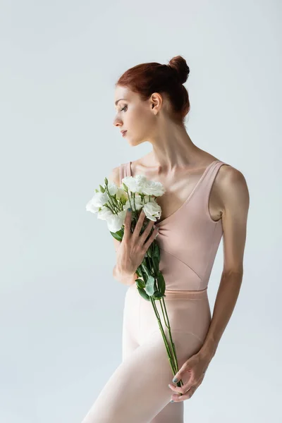 Redhead ballerina holding bouquet of flowers isolated on grey — Stock Photo