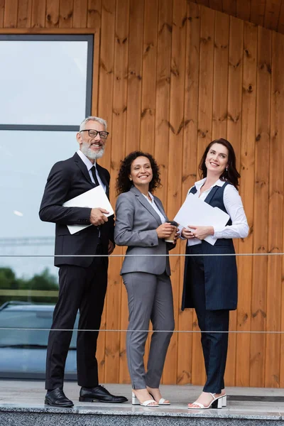 Geschäftspartner und Immobilienmakler lächeln in der Nähe von Gebäuden — Stockfoto