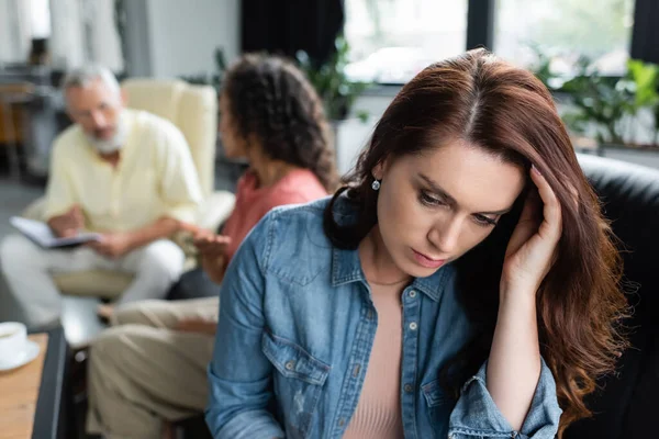 Depressed woman near african american girlfriend talking to psychologist on blurred background — Stock Photo