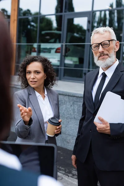 African american businesswoman pointing with hand near blurred realtor and middle aged colleague — Stock Photo