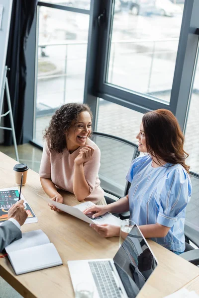 Interracial lesbians looking at each other near documents with mortgage graphs and real estate broker — Stock Photo