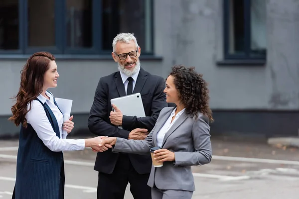 Happy realtor shaking hands with african american businesswoman near smiling middle aged man — Stock Photo