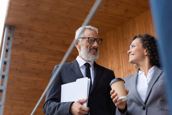 Smiling middle aged businessman talking to african american colleague outdoors — Stock Photo