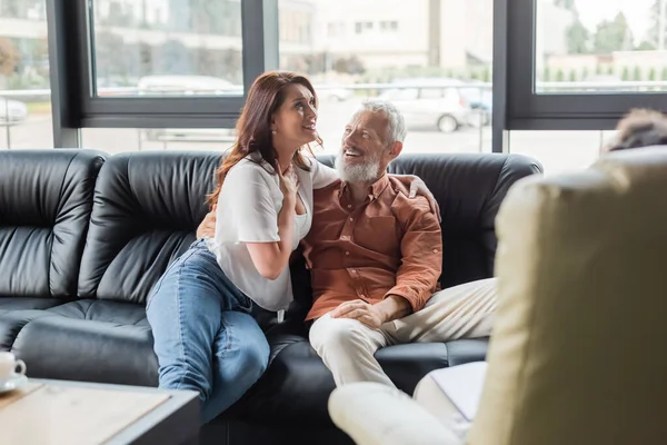 Donna felice toccando petto e abbracciando marito vicino psicologo offuscata in sala di consultazione — Foto stock