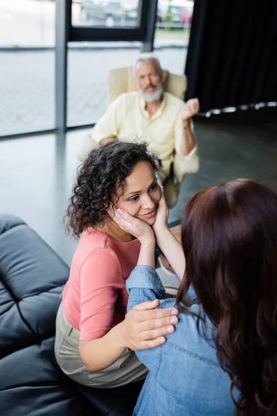Donna lesbica volto toccante di sorridente fidanzata afro-americana durante la consultazione psicologica — Foto stock