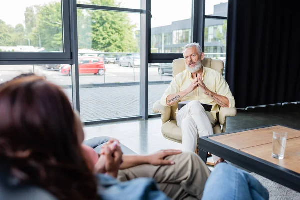 Psychologin mittleren Alters im Gespräch mit lesbischem Paar, das Hände auf verschwommenem Vordergrund hält — Stockfoto